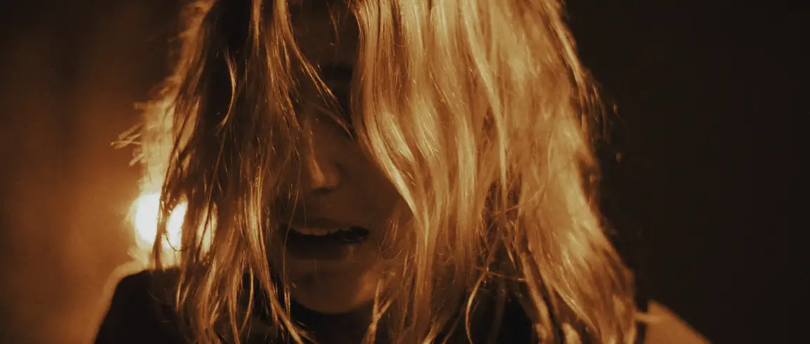 Anna: woman backlit by a warm lamp flare, tousled hair falling across her face, mouth parted