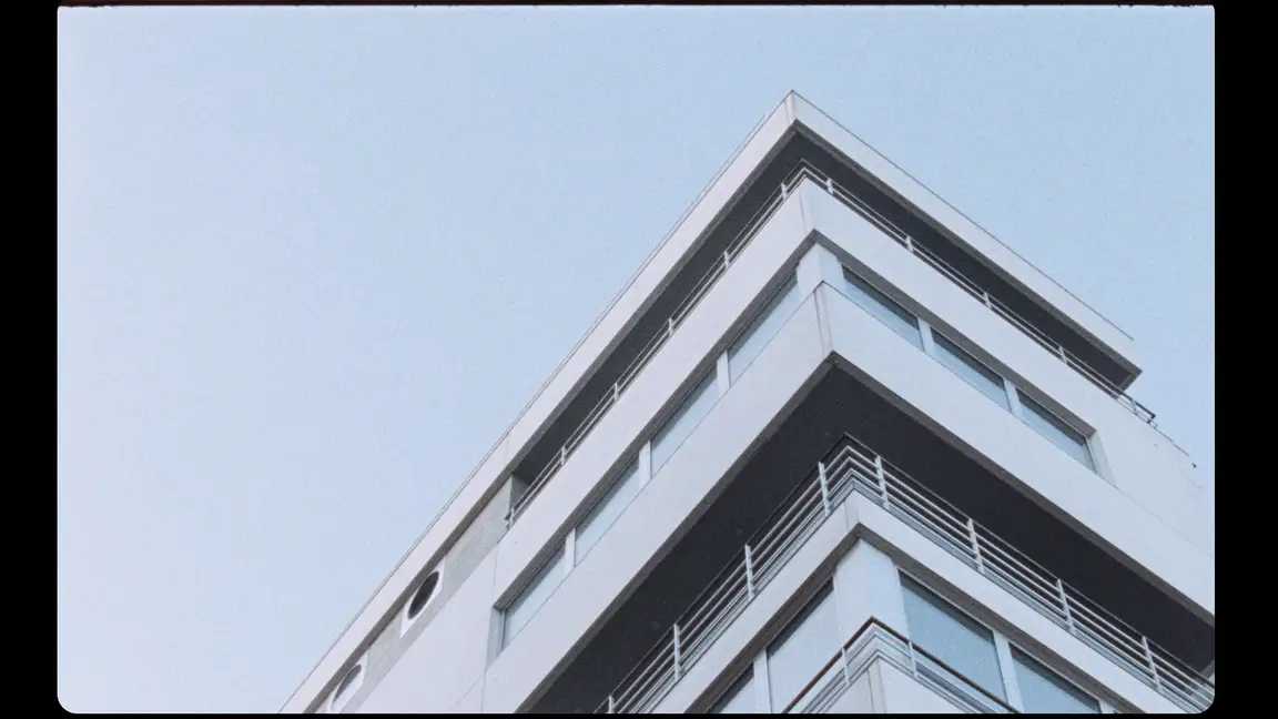 Hoge Blekker: low upward angle on the corner of a modern white apartment tower against a pale blue sky