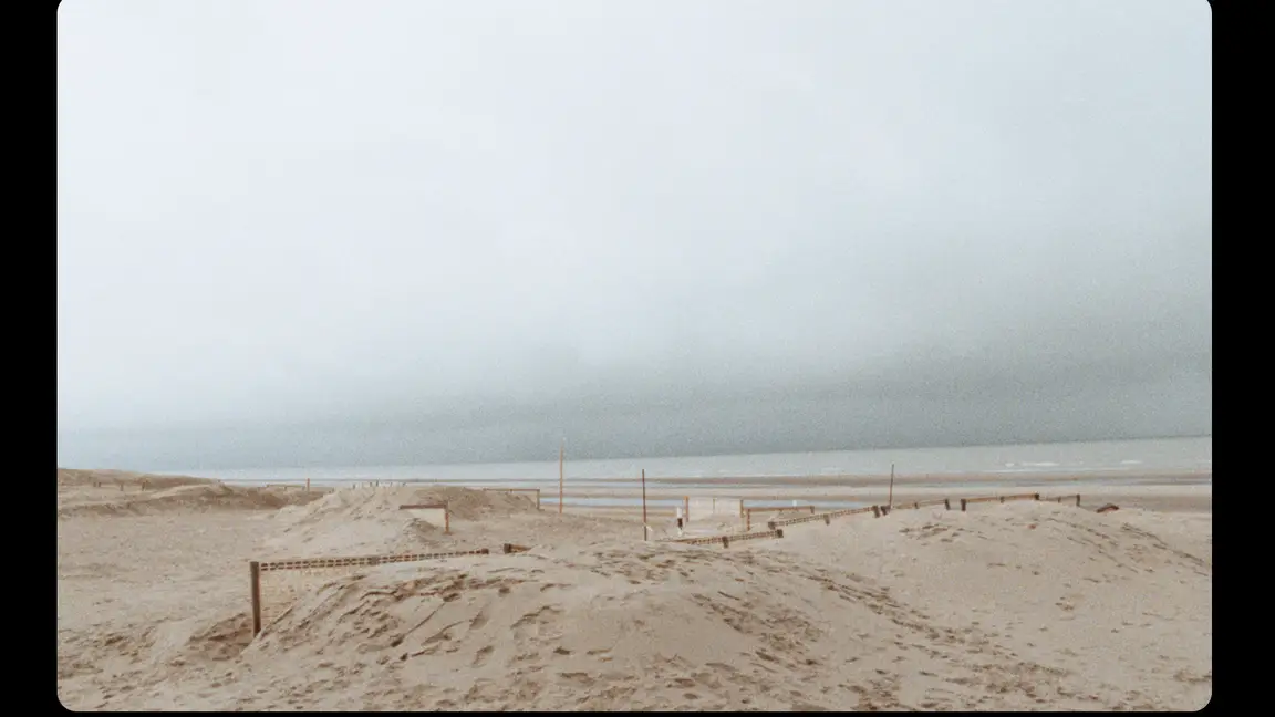 Hoge Blekker: rolling sand dunes with low wooden fences under a heavy overcast sky above a distant sea