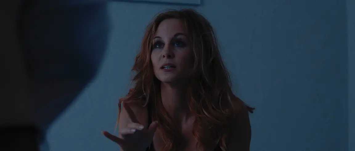 La Belle Rosine: red-haired woman gesturing mid-speech in cool blue bedroom light