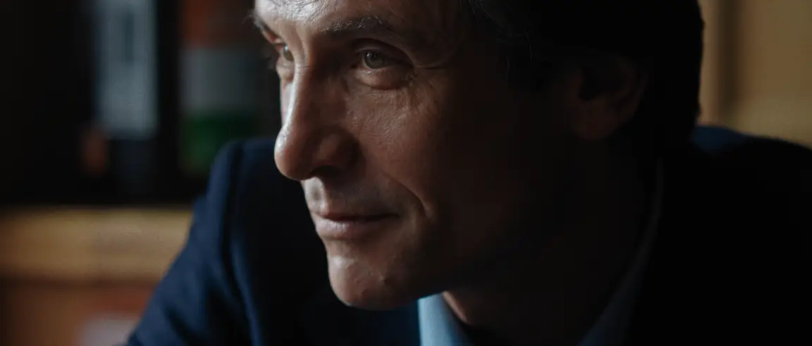 La Belle Rosine: close profile of the professor in a dark suit, warm light on his face