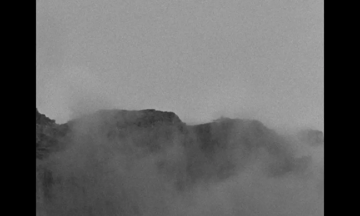 Ever Since, I Have Been Flying: grainy grey mountain ridges half hidden by drifting mist and cloud