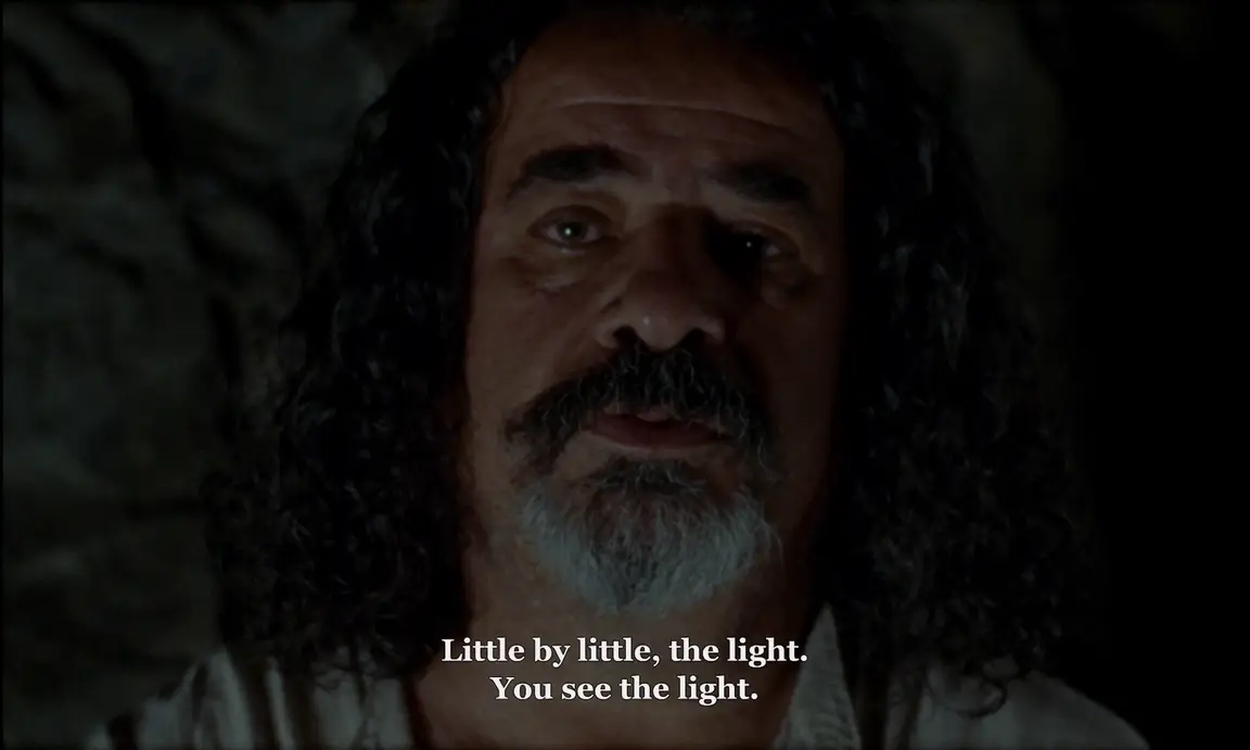 Ever Since, I Have Been Flying: dim close portrait of the older man speaking, subtitled about seeing the light