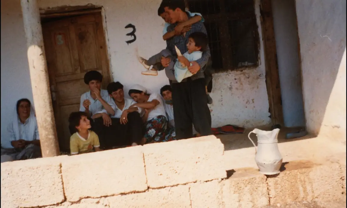 Ever Since, I Have Been Flying: an aged snapshot of a family gathered outside a whitewashed village house