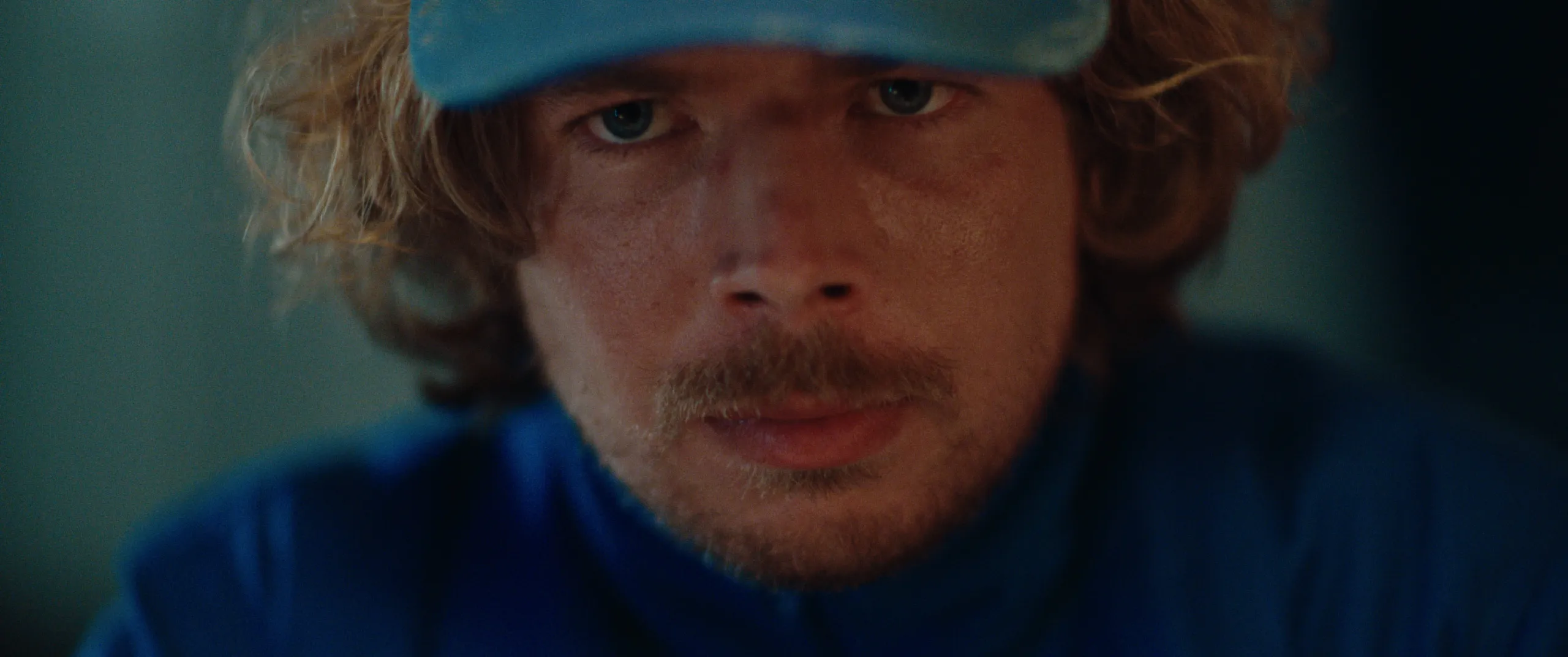 Vlinderman: extreme close up of Joop staring intently from under his blue cap brim