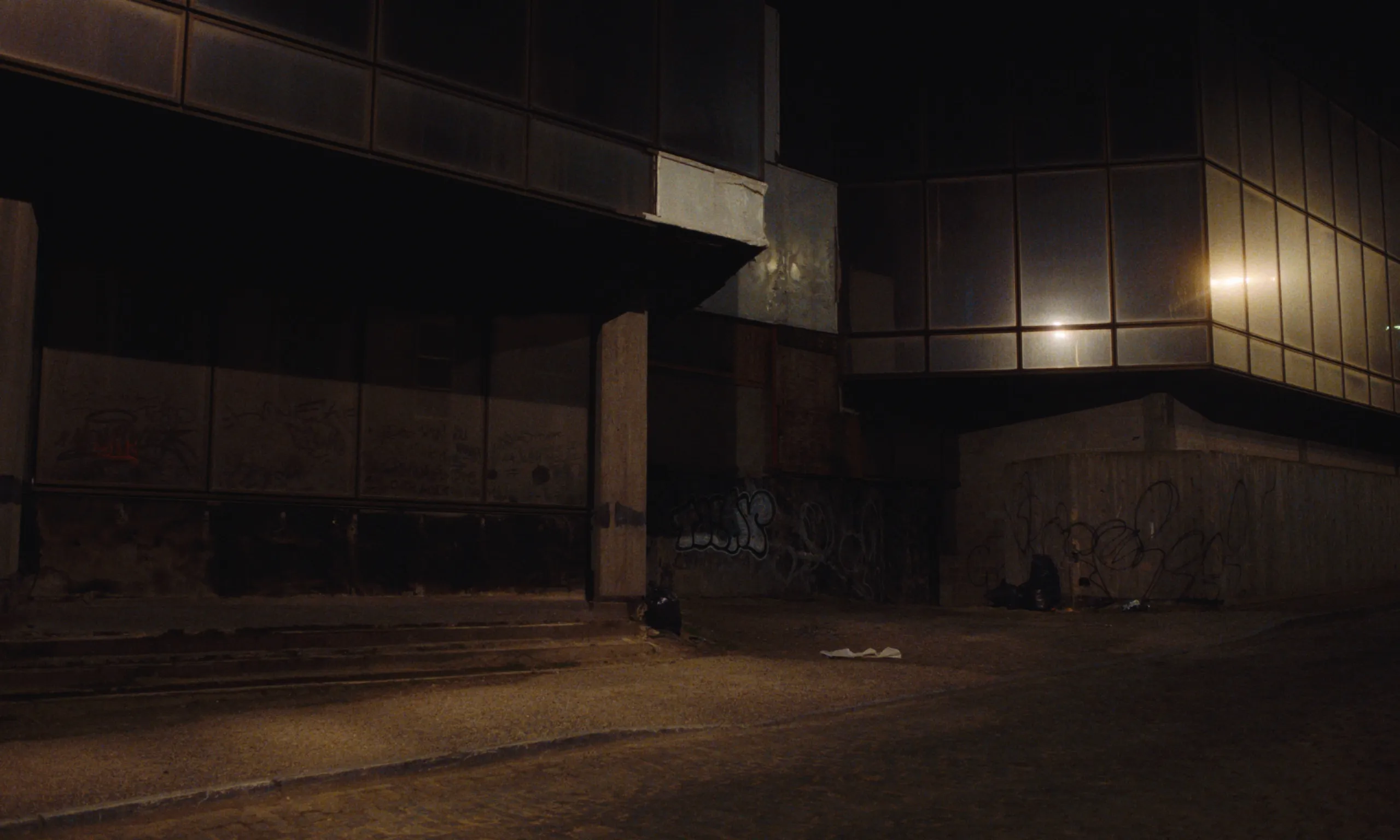 Burning Clouds: a deserted graffiti covered corner of a dark office building at night