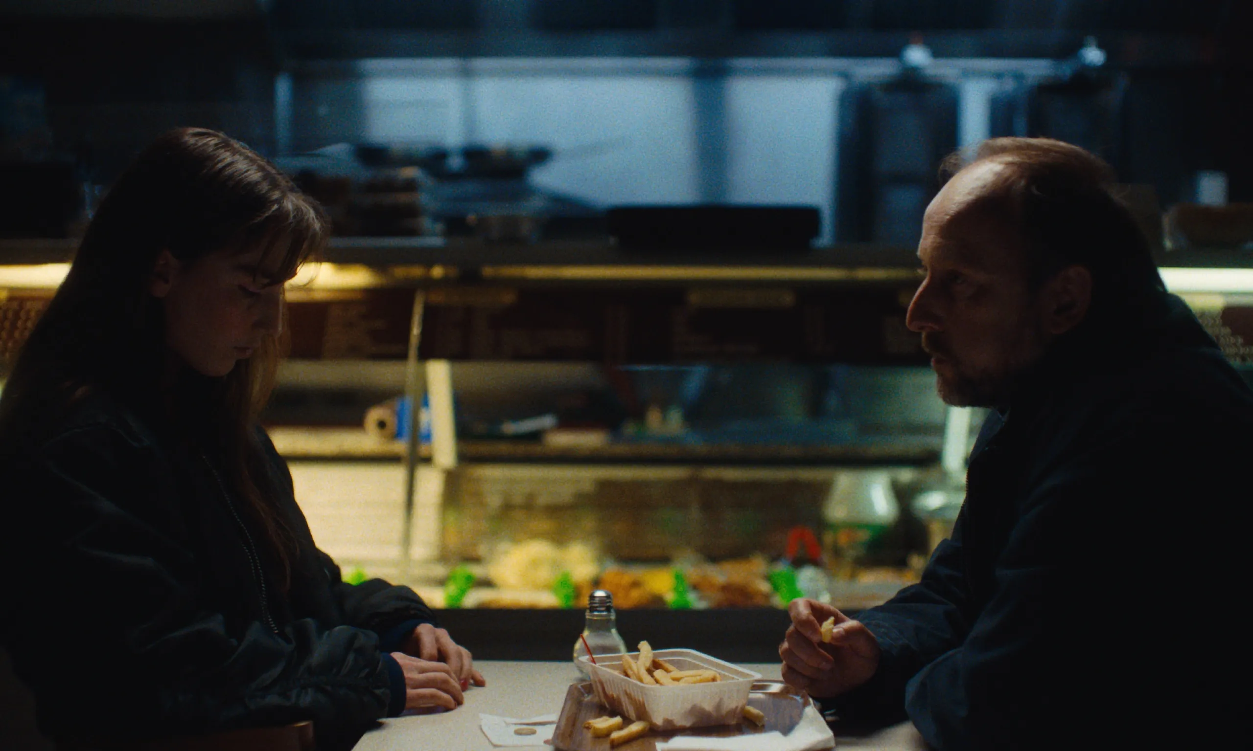 Burning Clouds: a young woman and an older man share fries at a late night snack bar table