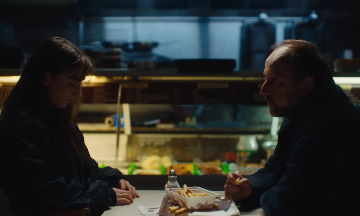 Burning Clouds: a young woman and an older man share fries at a late night snack bar table