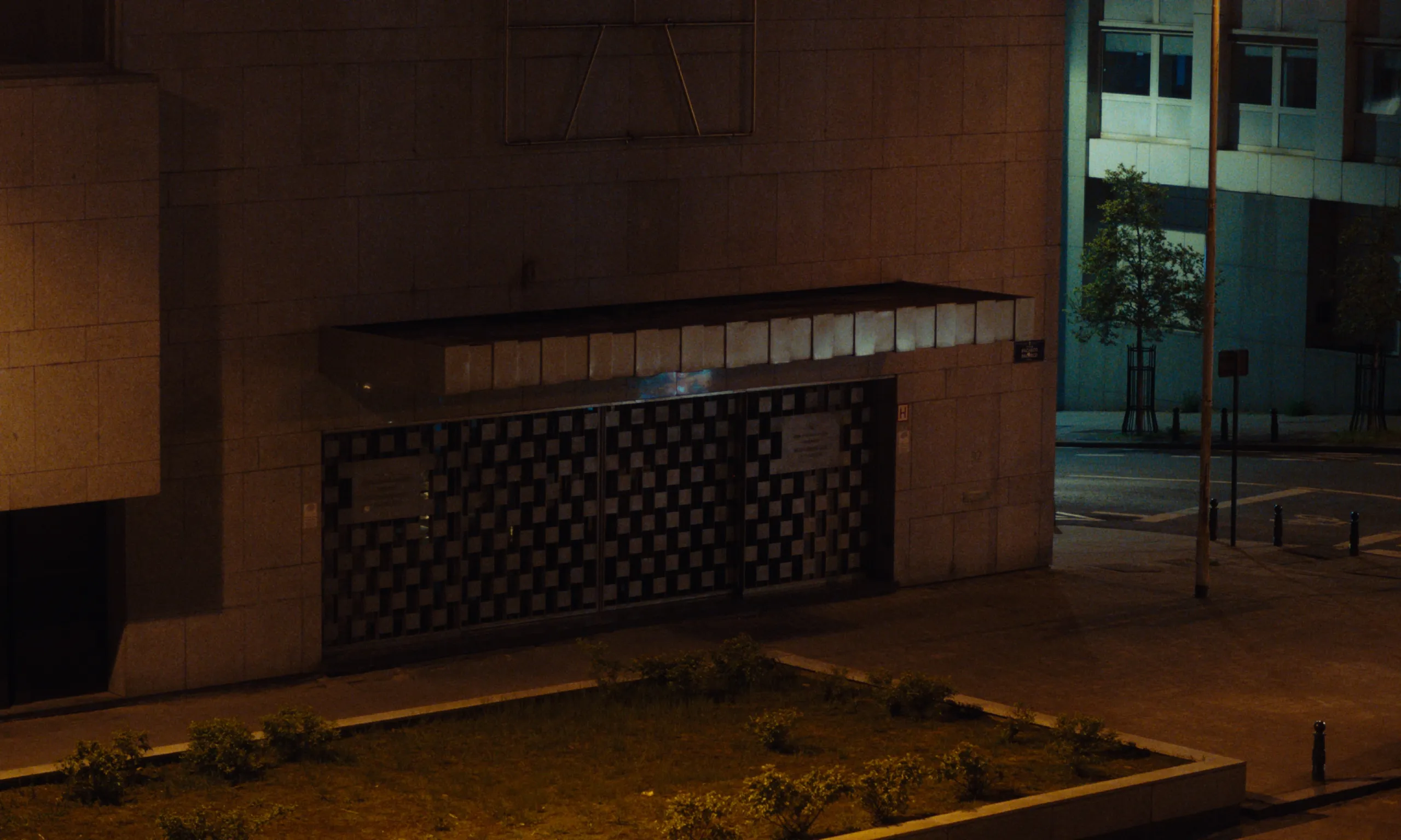 Burning Clouds: a shuttered checkered entrance of a stone building on an empty night street