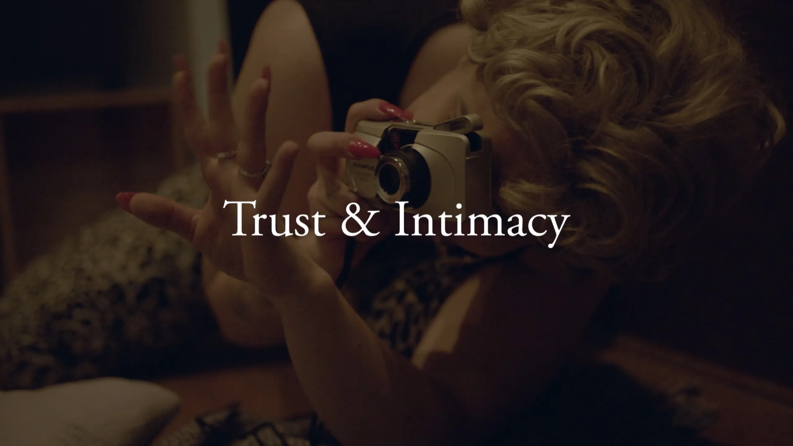 Chance Encounters: blonde woman lying down shooting an Olympus compact camera, Trust and Intimacy titled