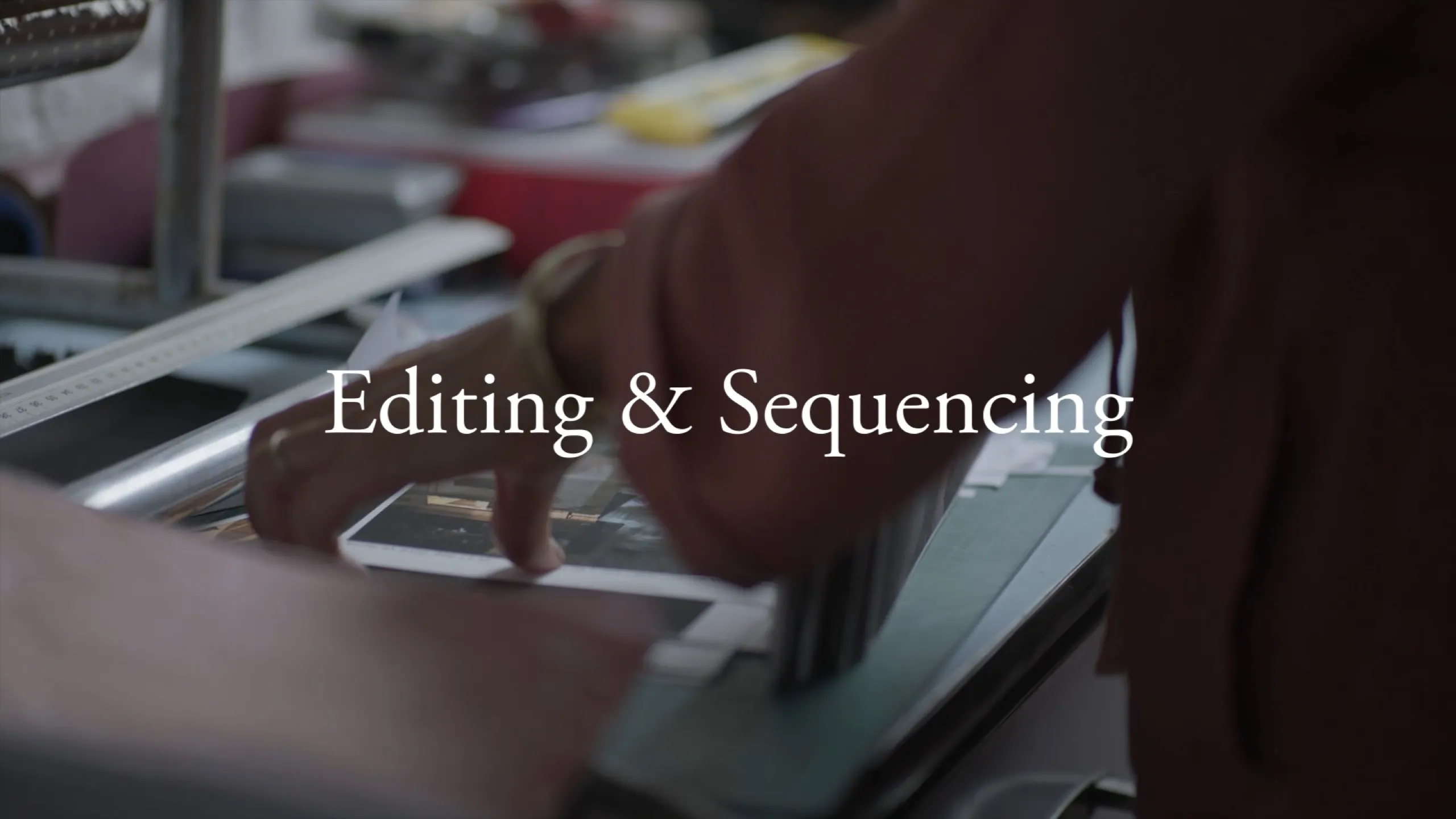Chance Encounters: hands arranging prints on a lightbox, Editing and Sequencing titled in warm light