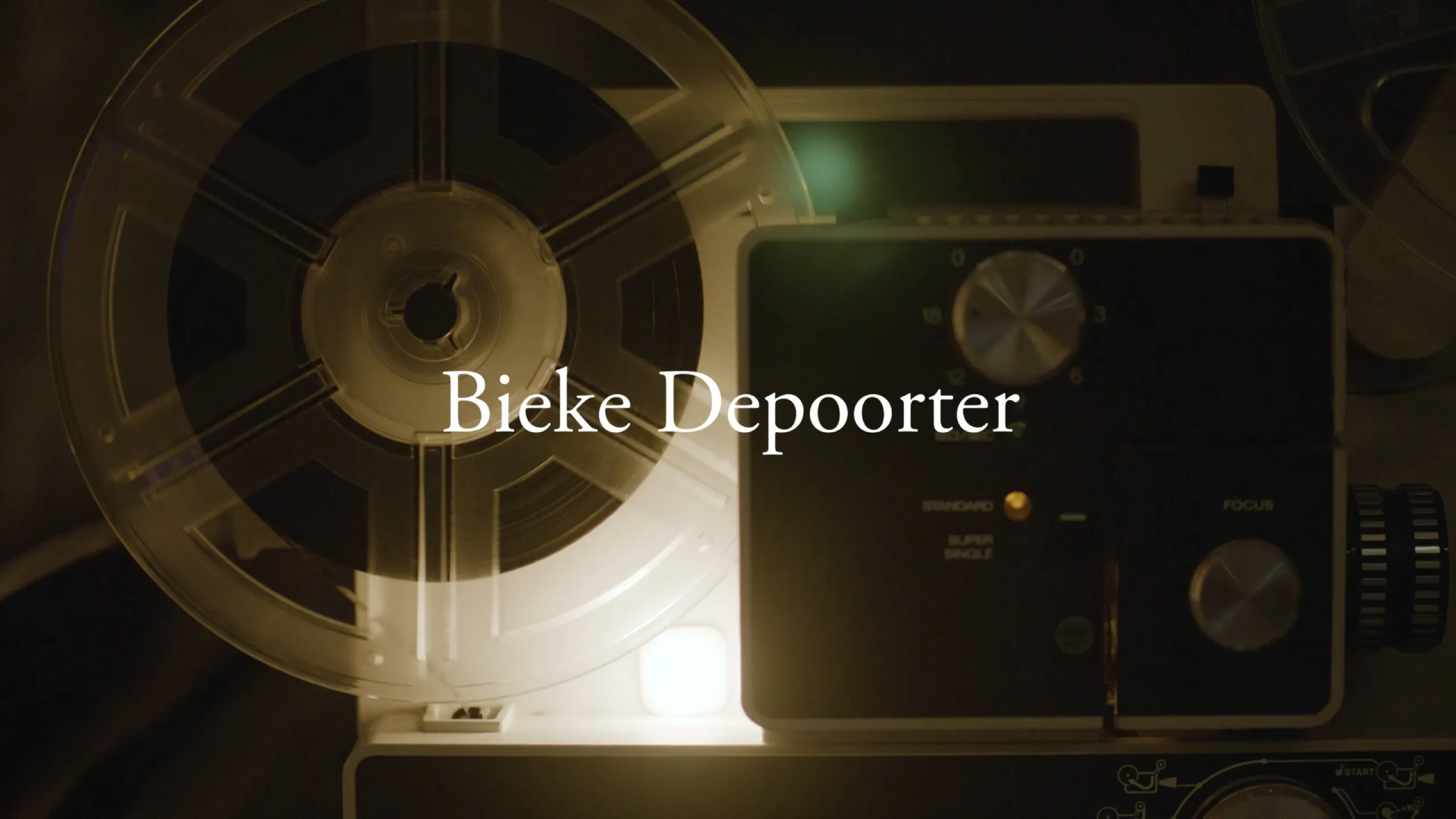 Chance Encounters: close view of a Super 8 projector reel and focus dial, Bieke Depoorter titled in amber light