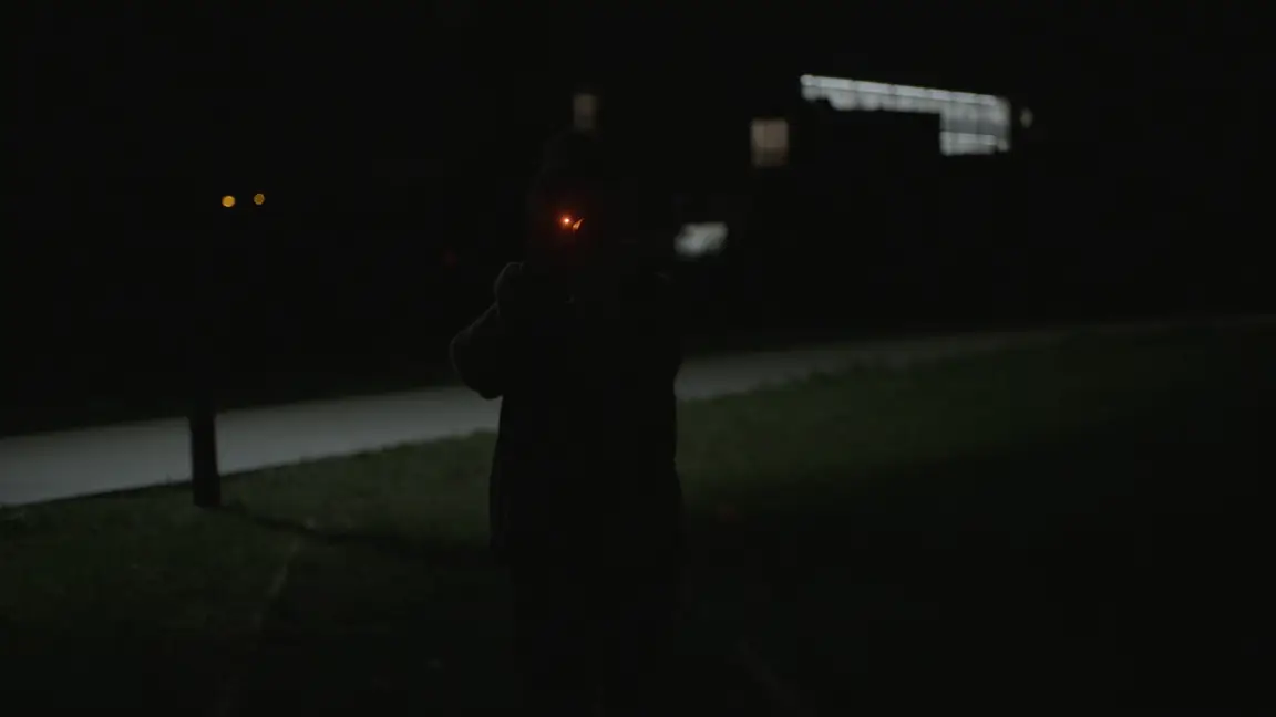 Chance Encounters: dark silhouette of a photographer at night, camera focus light glowing red