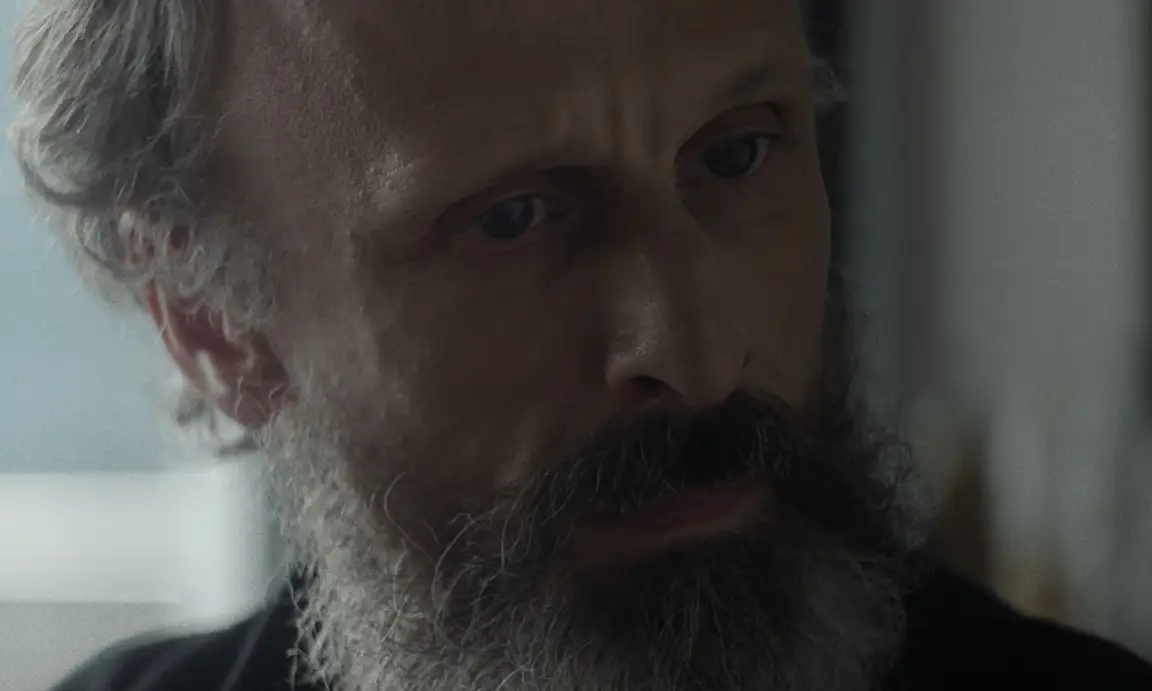Les Homards Immortels: extreme close-up of a grey-bearded man lowering his eyes in soft window light