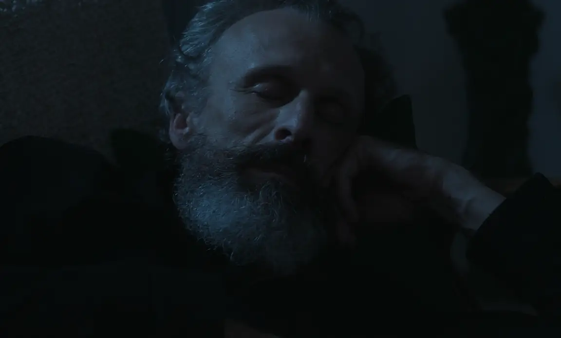 Les Homards Immortels: grey-bearded man sleeps with his head resting on his hand in blue night light