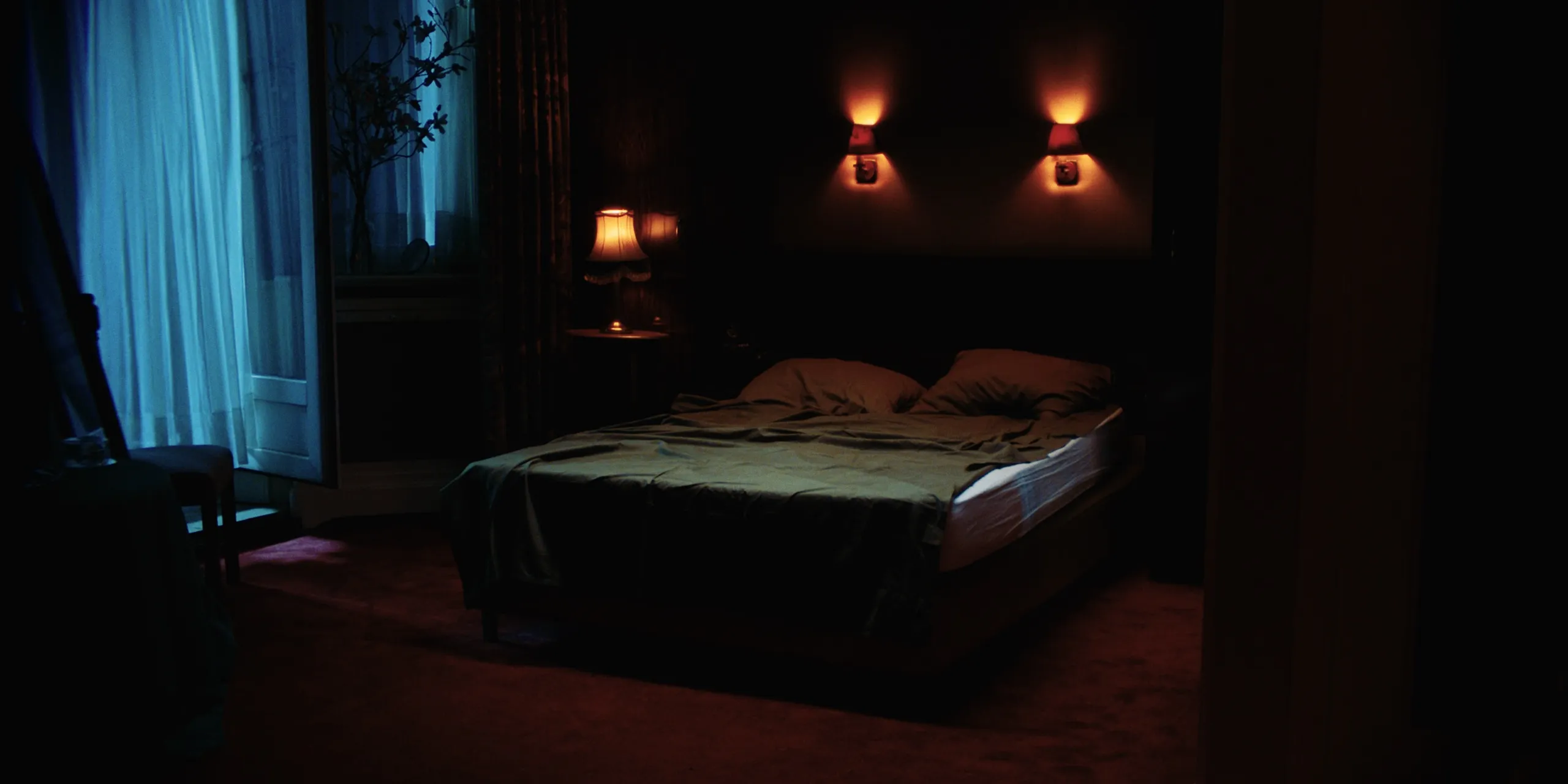 The Tears of Things: an empty made bed in a dim bedroom lit by warm wall sconces and cool window light