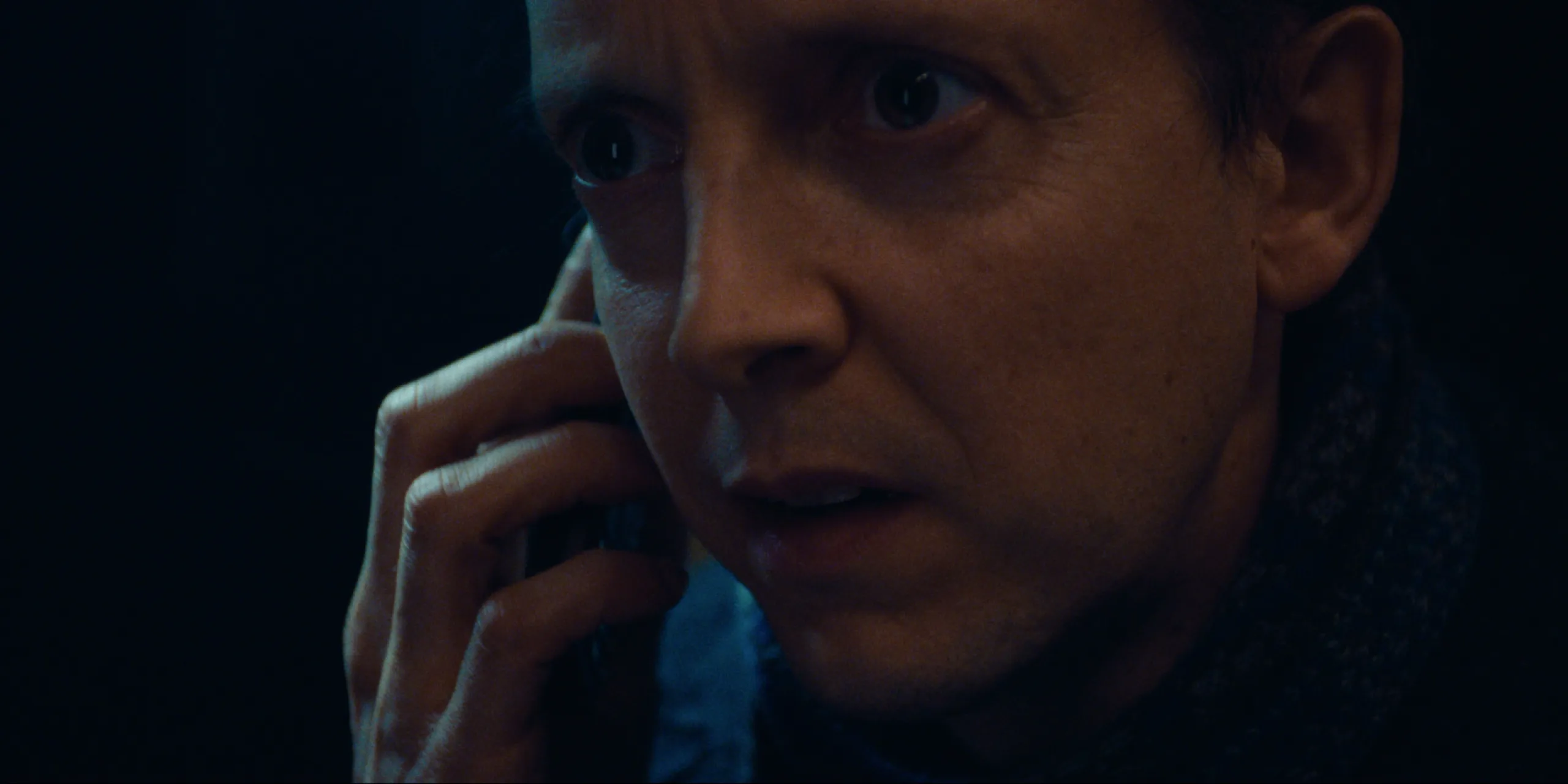 Bearer of Bad News: extreme close-up of Sven on the phone, eyes wide in the dark