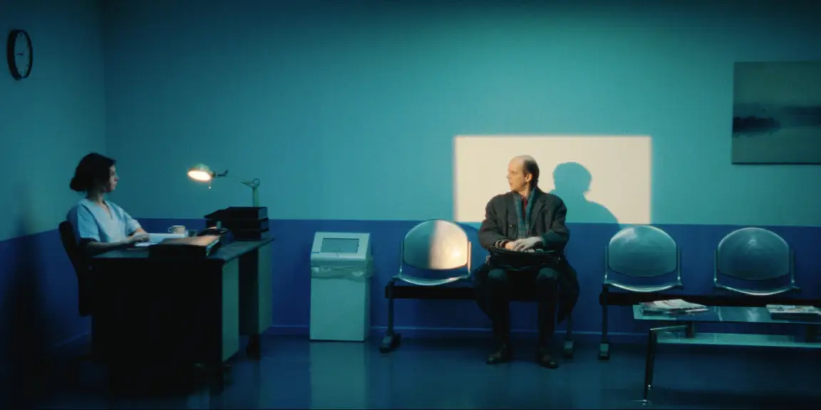 Bearer of Bad News: Sven waits with his bag in a blue clinic waiting room, receptionist at her desk